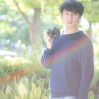 雨上がりの公園でフォトウォークをするカメラ男子の写真