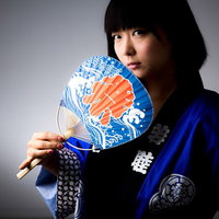 夏祭りに全力をかける半被姿の女性が扇子を掲げるの写真