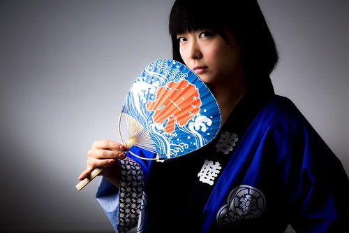 夏祭りに全力をかける半被姿の女性が扇子を掲げる