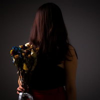 冷め切った関係を象徴する枯れた花束を握る女性の写真