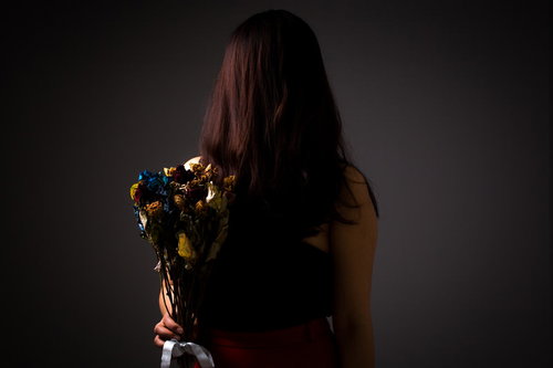 冷め切った関係を象徴する枯れた花束を握る女性