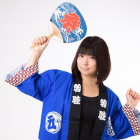 青い半被を着て和風うちわを掲げるお祭り女子の写真