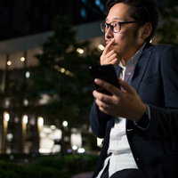 スマホのマップを確認しながら迷っている中間管理職の男性の写真