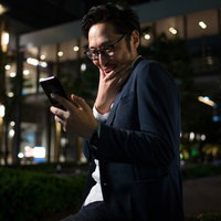 気になるあの子からのメールに思わずニヤける男性の写真