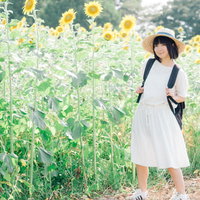 ひまわり畑の中で麦わら帽をかぶった彼女との夏休みの写真