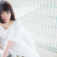 屋上のフェンス越しに見つめるワンピース姿の女性の写真