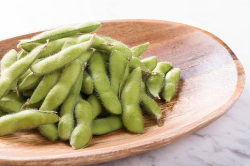 木のお皿に盛った塩がふりかかった茹で枝豆