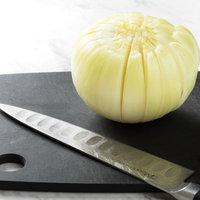 黒いまな板で16等分の切り込みが入った玉ねぎの写真