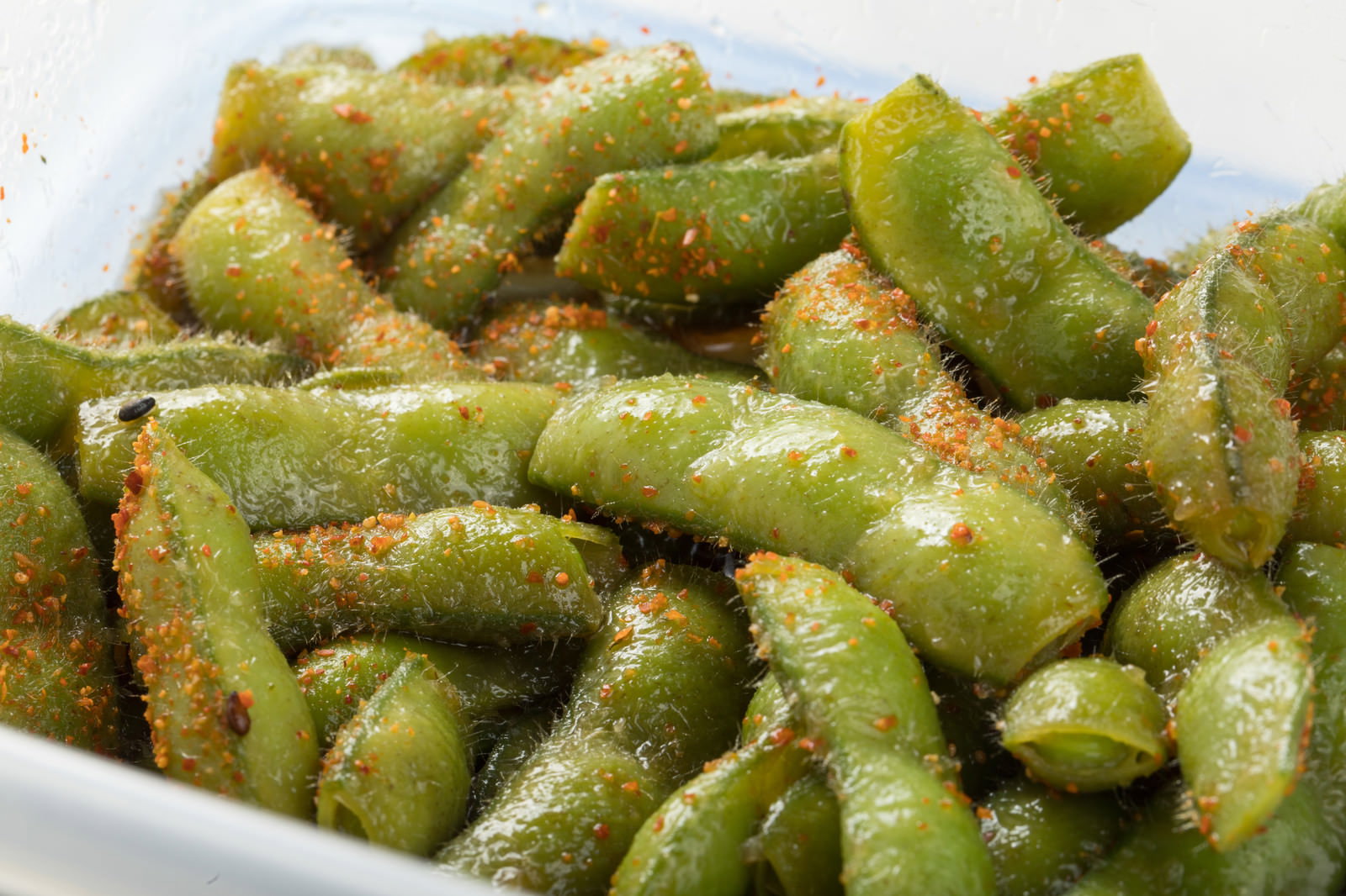 白い皿に盛られた枝豆に七味唐辛子がまぶされた状態