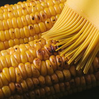 おいしかぁ～便の焼きとうもろこしに醤油ダレを塗るの写真