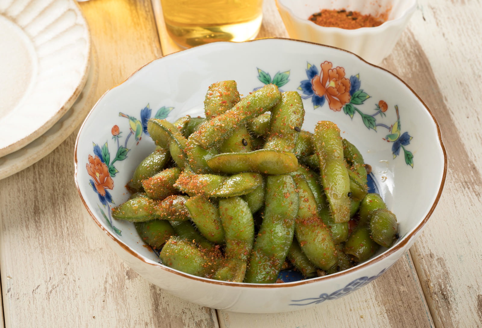 白い花柄の皿に盛られた七味唐辛子をまぶした枝豆料理