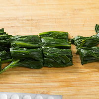 木製まな板の上でざく切りされたほうれん草の写真