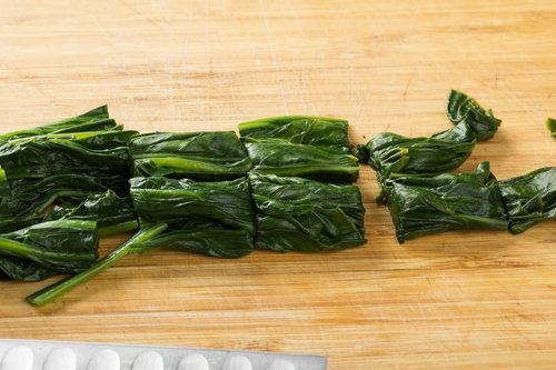 木製まな板の上でざく切りされたほうれん草