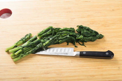 黒いまな板でほうれん草をざく切りする調理風景