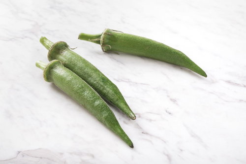 白背景に並ぶ新鮮なオクラ3本、五角形の断面と産毛がはっきり