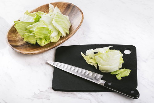 黒いまな板でレタスをざく切りしている調理工程