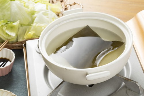 白い鍋で昆布から出汁を取る調理過程