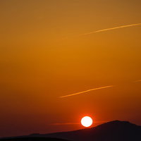 山の稜線に沈む太陽がオレンジに染める阿蘇の夕日の写真