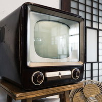 チャンネルをガチャガチャ回す古いブラウン管テレビの写真