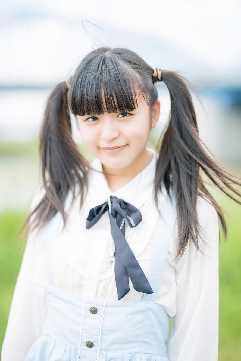 ツインテールの女の子が屋外で笑顔を見せる写真［モデル：こころ］