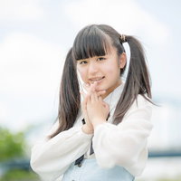 両手を顔に添えて笑うツインテールの女性の写真