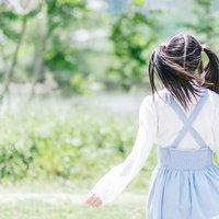 ツインテール女子が緑の公園で見つめる後ろ姿の写真
