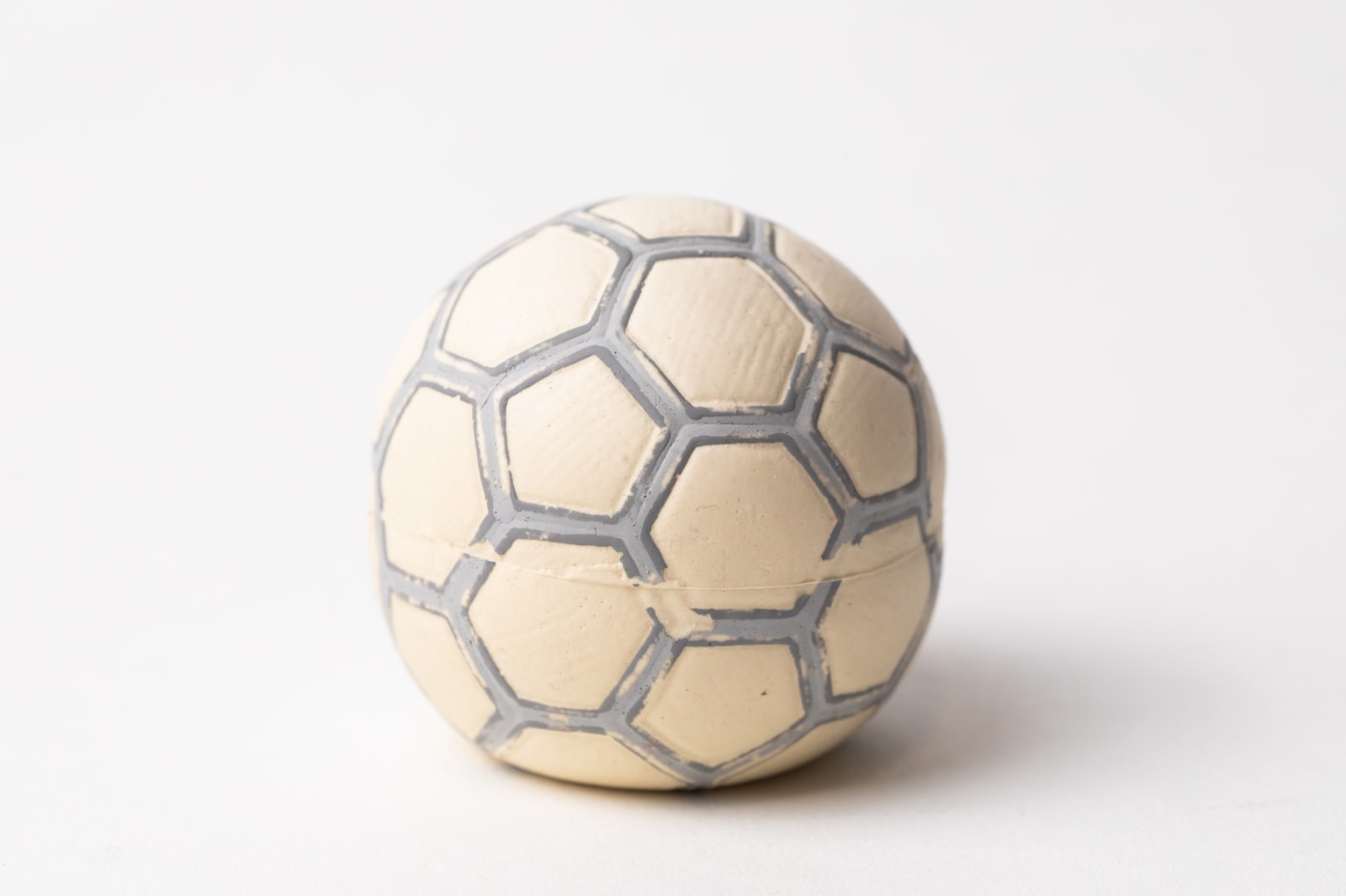 白い背景に置かれたクリーム色のペット用サッカーボール