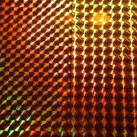 緑と橙色に光るホログラムの立体格子パターンとプリズムの写真