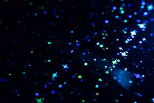 黒い背景に青と緑にきらめく星とキラキラパーティクル