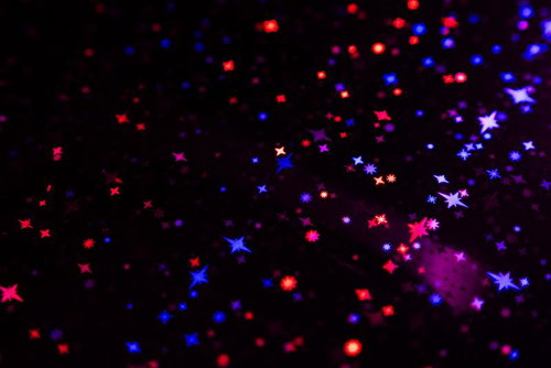黒背景に赤と青に光るキラキラした星の粒子表現と輝きの背景