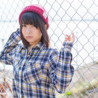 フェンスにもたれるピンク帽子姿の女性のポートレートの写真