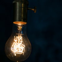 暗い背景に浮かぶオレンジ色のフィラメント電球の写真