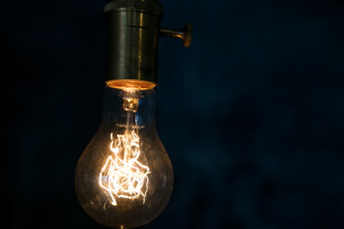 暗い背景に浮かぶオレンジ色のフィラメント電球