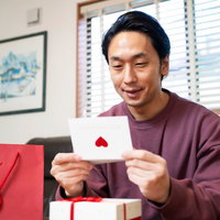 ラブレターを読んでにんまりする紫色セーターの男性の写真