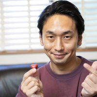 ハート型のチョコレートと指ハートをする男性の写真