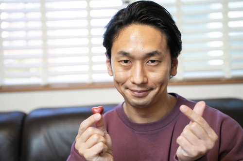 ハート型のチョコレートと指ハートをする男性