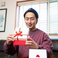 バレンタインデーにプレゼントをもらって喜ぶ男性の写真