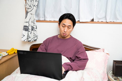 寒くてベッドから出られない在宅ワーカーの男性
