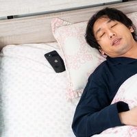 朝寝坊で遅刻する男性がアラームが鳴っているのに爆睡しているの写真