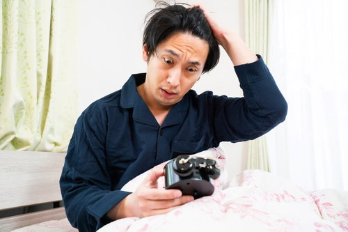 飛び起きるがすでに時おすし、目覚まし時計を見て慌てる男性