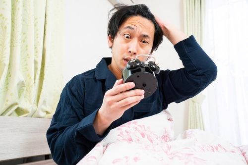 アラームをセットし忘れて寝坊し慌てる男性