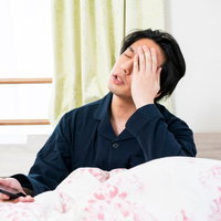 寝坊してクライアントからの大量通知で頭が痛い男性の写真