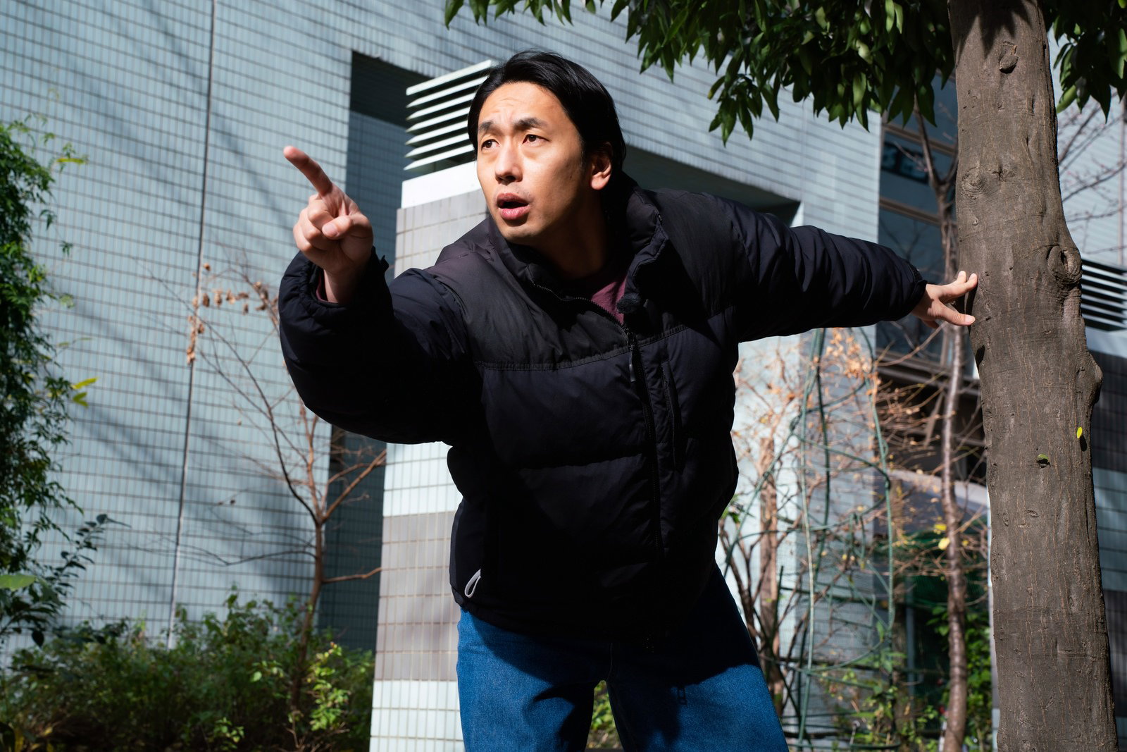 黒い服を着た男性が指をさして驚いた表情を見せている［モデル：大川竜弥］