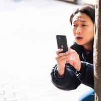 街で見かけたトラブルを壁の陰からスマホで激写する男性の写真