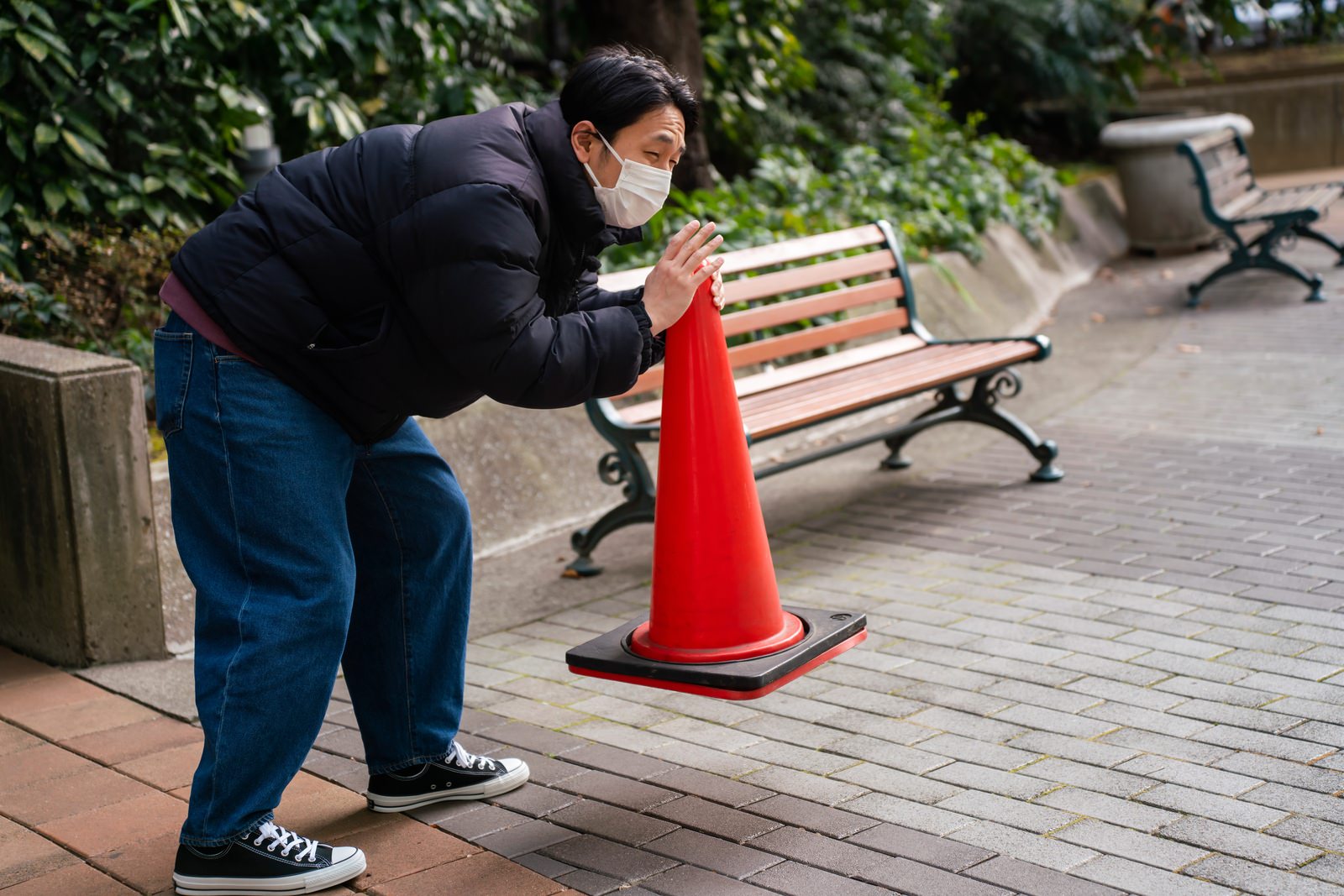 木製デッキで赤い三角コーンを設置している男性