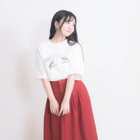 白いTシャツと赤いロングスカートでポージングする女性の写真