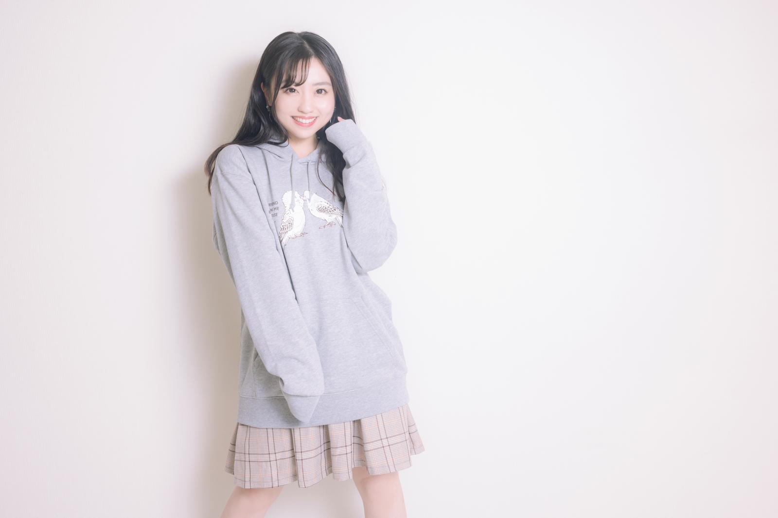 グレーのインコパーカーを着て笑顔でポーズする女性［モデル：河村友歌］