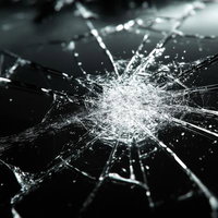 割れたガラスに走るひび割れと光の軌跡、破損の衝撃表現の写真