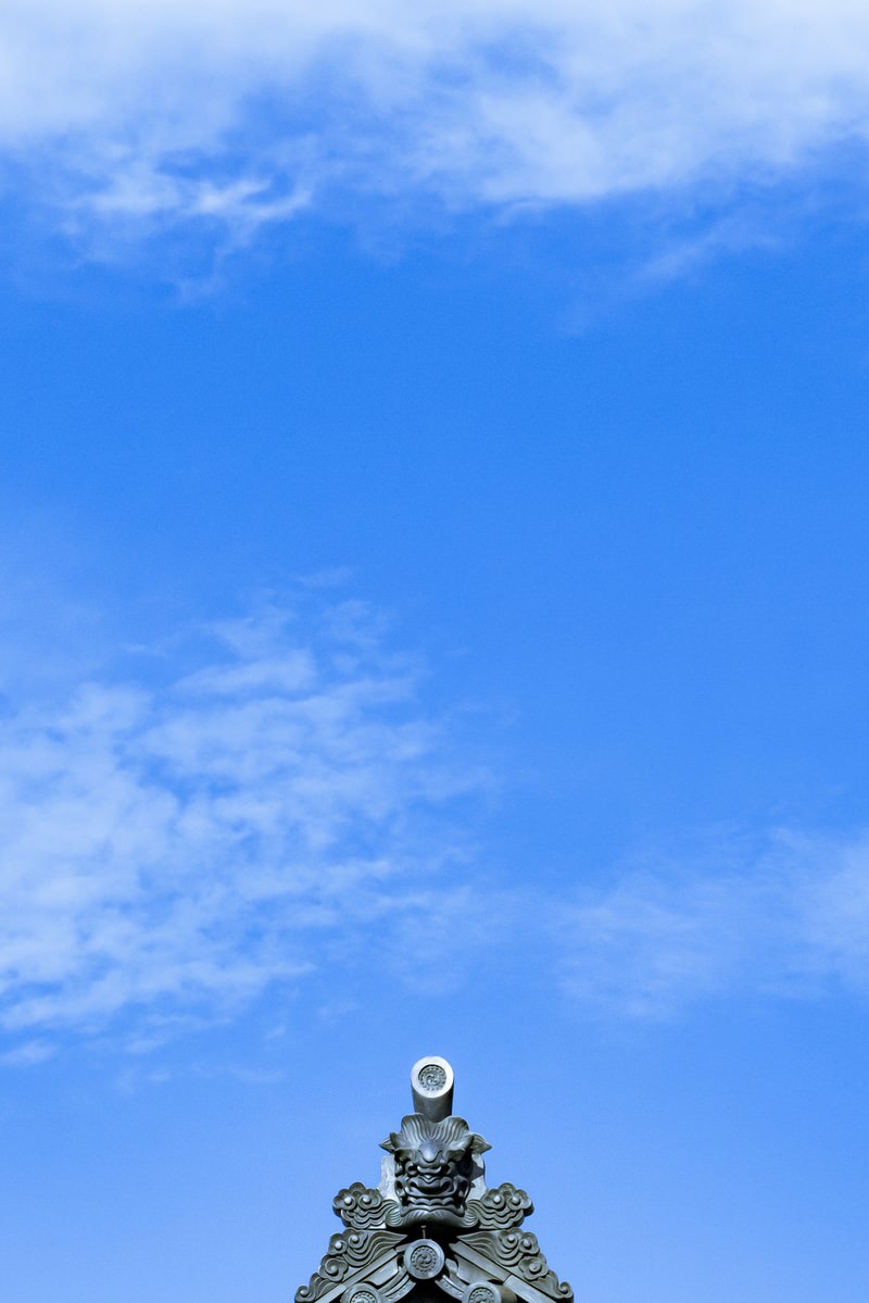 寺社建築の屋根に立つ鬼瓦と青空