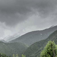 曇り空に連なる緑豊かな山脈の重層的風景の写真